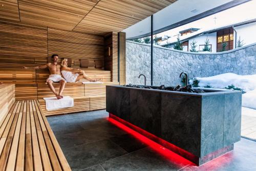 a bathroom with two people sitting in a sauna at Granbaita Dolomites in Selva di Val Gardena