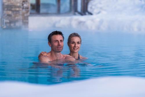 a man and woman swimming in a swimming pool at Granbaita Dolomites in Selva di Val Gardena