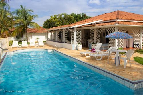 uma piscina com cadeiras e um guarda-sol ao lado de uma casa em Recanto Serenissima em São Pedro
