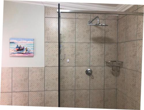 a shower with a glass door with a painting at Baylight Accomodation in Mossel Bay