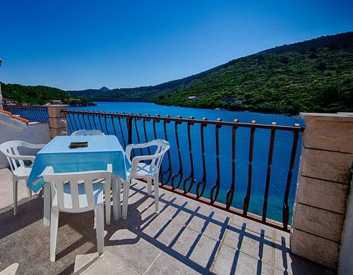 einen Tisch und Stühle auf einem Balkon mit Blick auf das Wasser in der Unterkunft Apartments Malo Lago in Lastovo