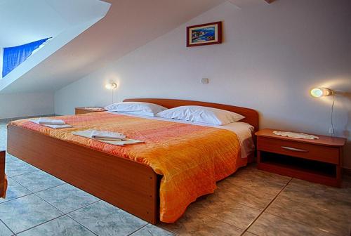 ein Schlafzimmer mit einem großen Bett mit einer orangefarbenen Decke in der Unterkunft Apartments Malo Lago in Lastovo