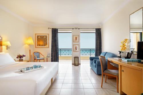 a hotel room with a large bed and a desk at Mitsis Lindos Memories Resort & Spa in Líndos