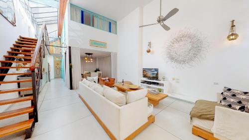 a living room with a white couch and a staircase at Bohemian Villa Rooftop in Neve Tzedek by HolyGuest in Tel Aviv