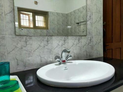 Un lavabo blanco en un baño con espejo. en Anashwara, en Kozhikode