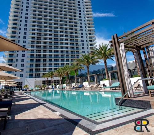a swimming pool with chairs and a tall building at HYDE Beach House Apartments in Hollywood