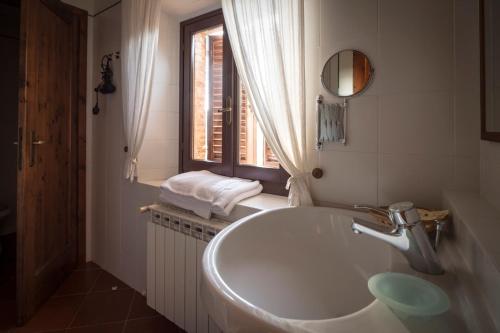 un bagno bianco con lavandino e finestra di Collelungo a Castellina in Chianti
