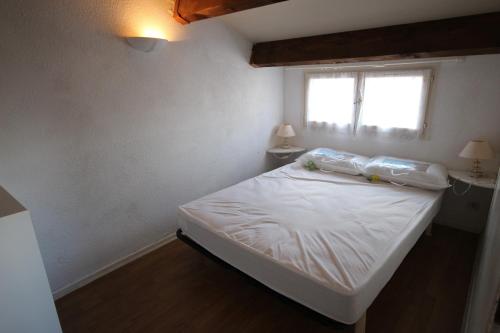 ein kleines Schlafzimmer mit einem weißen Bett und einem Fenster in der Unterkunft Maison T2 cabine 4 couchages, terrasse clôturée -résidence Sun village avec piscine commune, 300m de la plage à PORTIRAGNES LRSUNO5 in Portiragnes