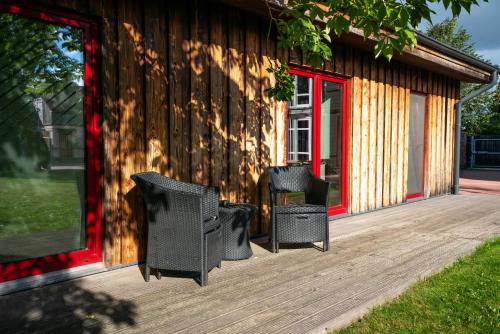 een houten terras met 2 stoelen en een gebouw bij Altribute Studio w Sauna Secure Parking wifi 90mbs in Liepāja