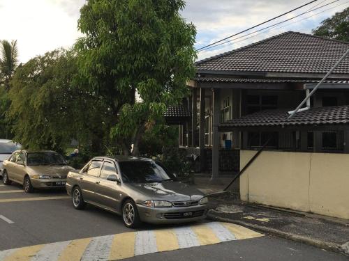 dos autos estacionados en una calle frente a una casa en Pandan Home Stay en Alor Setar