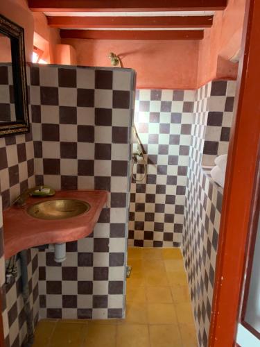 a bathroom with a sink and a checkered wall at Riad Darbask in Essaouira