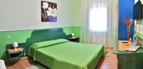una camera verde con un letto verde e una finestra di B&B Mitzixeddas Sa Domu de Braxia a Màndas