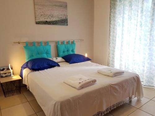 a bedroom with a large white bed with blue pillows at Le Gecko Vert in Manapany-les Bains