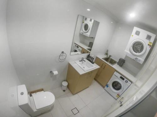 a white bathroom with a toilet and a washing machine at 1 Bdrm Close Airport/Shops, WIFI, NETFLIX, PARKING in Perth