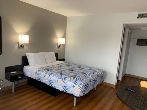 a small bedroom with a bed and a table at Motel 6-Dayton, OH in Dayton
