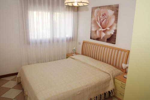 リド・ディ・イエゾロにあるFamily Apartments Residence Triesteのベッドルーム1室(ベッド1台付)が備わります。壁に花の絵が飾られています。