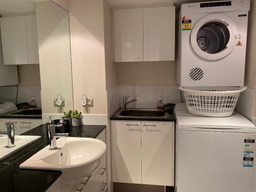 a white kitchen with a sink and a washing machine at ARENA RESORT STYLE EXEC FREE NETFLIX WIFI WINE in Perth
