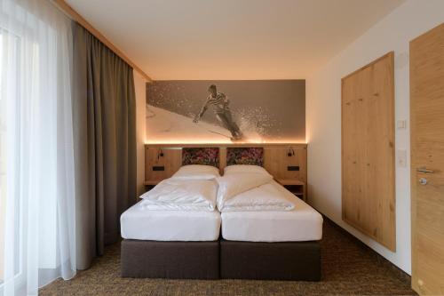 pokój hotelowy z łóżkiem i zdjęciem surfera w obiekcie Arula GmbH w mieście Sankt Anton am Arlberg