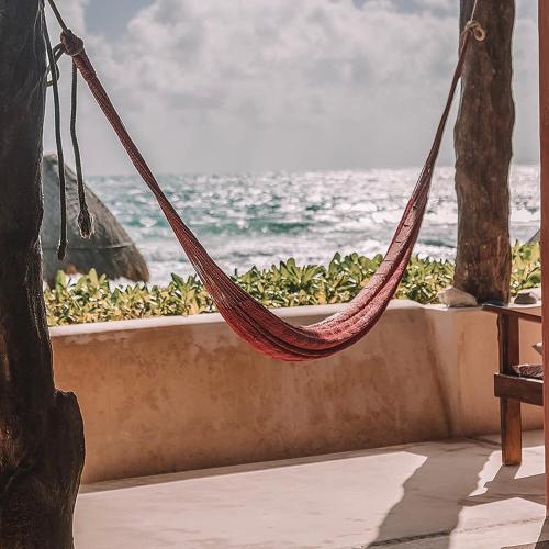 a hammock hanging from a wall near the ocean at La Conchita Tulum in Tulum