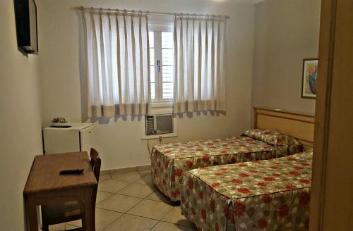 um quarto de hotel com duas camas e uma mesa em Hotel Vila do Conde em Itu