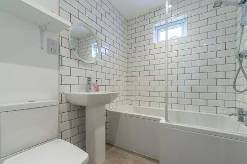 a white bathroom with a sink and a bath tub at Miss Fishers in Port Isaac