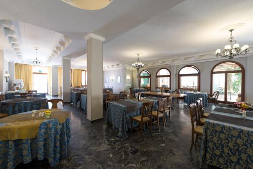 Hotel Corallo في مونتيكاتيني تيرمي: مطعم بطاولات زرقاء وكراسي ونوافذ