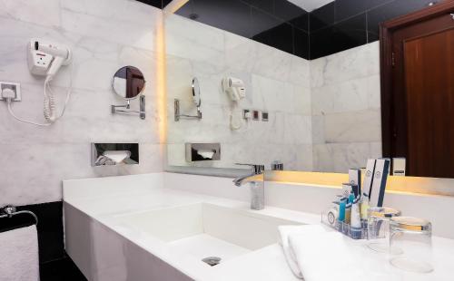 a white bathroom with a sink and a phone at Jeddah Oasis Hotel in Jeddah