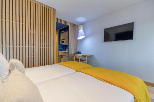 a bedroom with a bed with a yellow blanket on it at Praia do Sal Resort in Alcochete