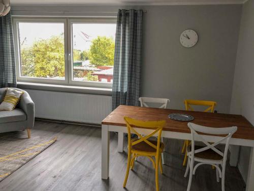 ein Wohnzimmer mit einem Tisch, Stühlen und einer Uhr in der Unterkunft 168 Salzwiese Ferienwohnung in Accumersiel