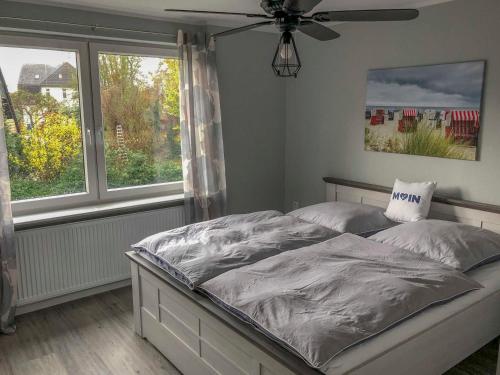 a bedroom with a bed with a fan and windows at 168 Salzwiese Ferienwohnung in Accumersiel