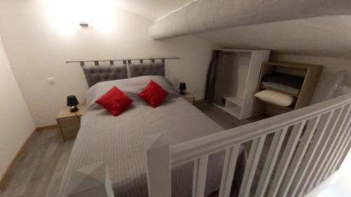 - une chambre avec un lit et 2 oreillers rouges dans l'établissement L'appartement de l'église, à Saintes-Maries-de-la-Mer