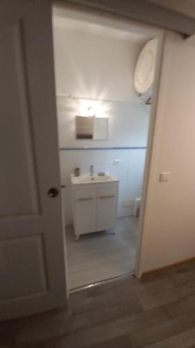 La salle de bains est pourvue d'un lavabo et d'un mur blanc. dans l'établissement L'appartement de l'église, à Saintes-Maries-de-la-Mer