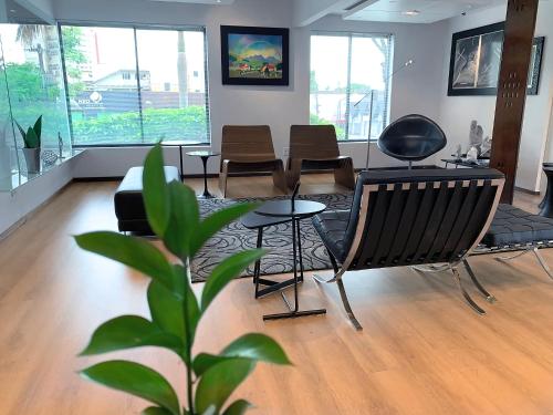 a living room with a couch and chairs and a plant at Hotel Germânia in Joinville