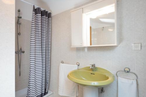 uma casa de banho com um lavatório amarelo e um espelho. em Apartment Roce em Rabac