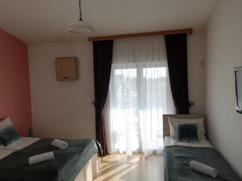 a bedroom with two beds and a large window at Hotel Malta in Mostar