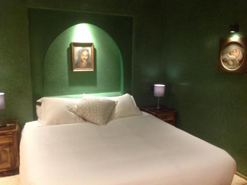 a bedroom with a white bed with a green wall at MAROC LODGE Atlas Mountain Retreat in Amizmiz