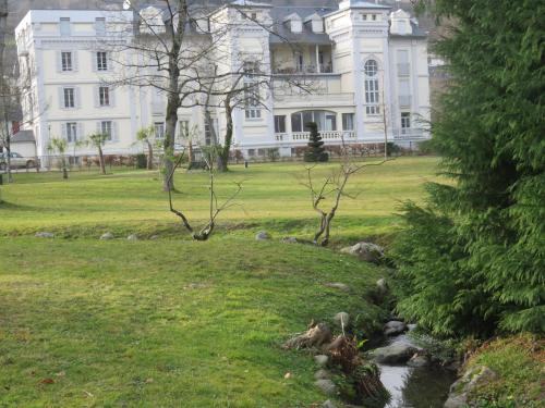a large white house with a stream in front of a yard at Le Balcon du Parc, entre Lourdes et Gavarnie in Argelès-Gazost
