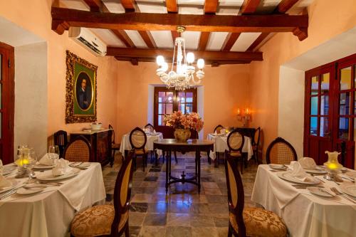 a dining room with tables and chairs and a chandelier at Hotel Boutique Casa Don Gustavo, Campeche in Campeche
