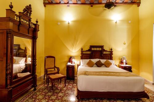 a bedroom with a large bed and a chair at Hotel Boutique Casa Don Gustavo, Campeche in Campeche