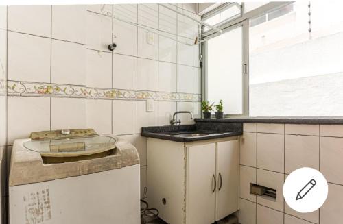 a kitchen with white tiled walls and a sink at Edifício Andressa in Florianópolis