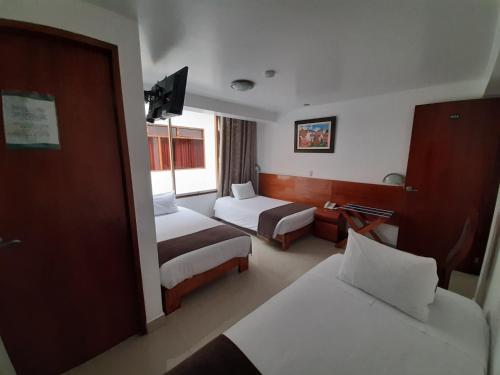 a hotel room with two beds and a television at Flower's House MachuPicchu in Machu Picchu