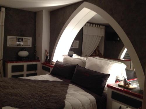 a bedroom with a large bed with an archway at LA BASTIDE DES 3 AS & Spa in Vriange