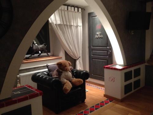 a teddy bear sitting in a chair in a room at LA BASTIDE DES 3 AS & Spa in Vriange
