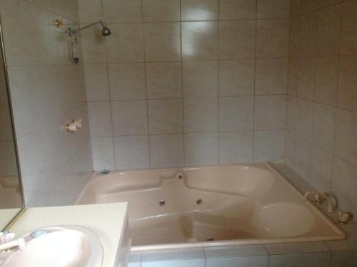 a white bath tub in a bathroom with a sink at Quality Inn Colonial in Bendigo
