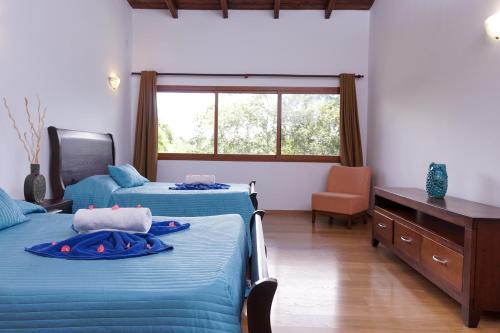 a bedroom with two beds and a desk and a window at Sybaris Suites & Residences in Juan Dolio