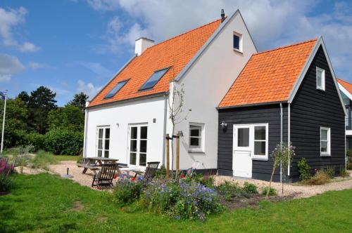 een zwart-wit huis met een oranje dak bij DE DUINDISTEL Bed by the Sea in Dishoek