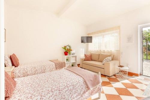 a bedroom with two beds and a couch and a tv at Casa do Riacho in Esposende