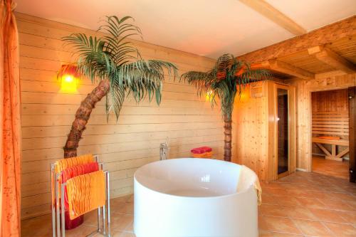 a bathroom with a tub and a palm tree at Mathiasl Wellness-Ferienhäuser in Bodensdorf