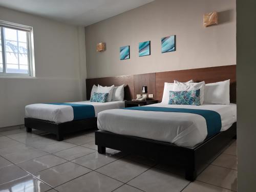 a hotel room with two beds and a window at Hotel Pabela in Ocotlán