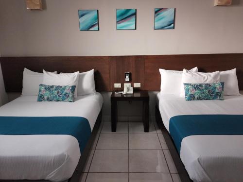 a hotel room with two beds and two tables at Hotel Pabela in Ocotlán